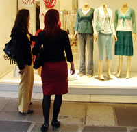 Duas mulheres olhando uma vitrine de loja de roupas