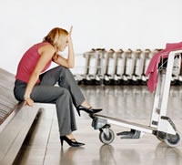 Mulher apoiando o pé no carrinho de bagagem do aeroporto
